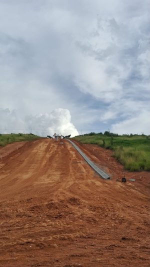 Avanço da terraplenagem e das guias em uma via do loteamento