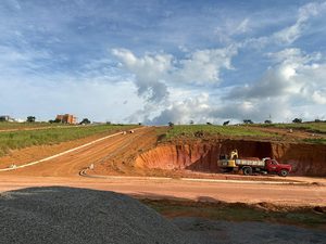 Corte de terra em uma via do loteamento, com caminhão e escavadeira