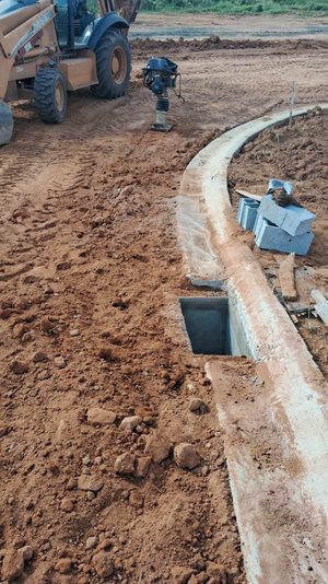 Guias de concreto e boca de lobo sendo instaladas em uma via do loteamento