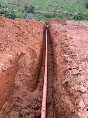 Tubulação da rede instalada em vala profunda, com área verde ao fundo