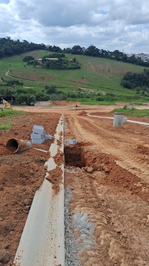Guias de concreto e poço de visita sendo instalados em uma via do loteamento